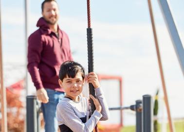 Child on a swing with parent behind them